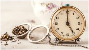 Vintage alarm clock with tea strainer on the white table