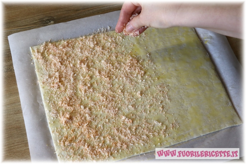 Mescoliamo in una ciotola i formaggi con la paprika e cospargiamoli sulla pasta sfoglia in modo da ricoprirla completamente