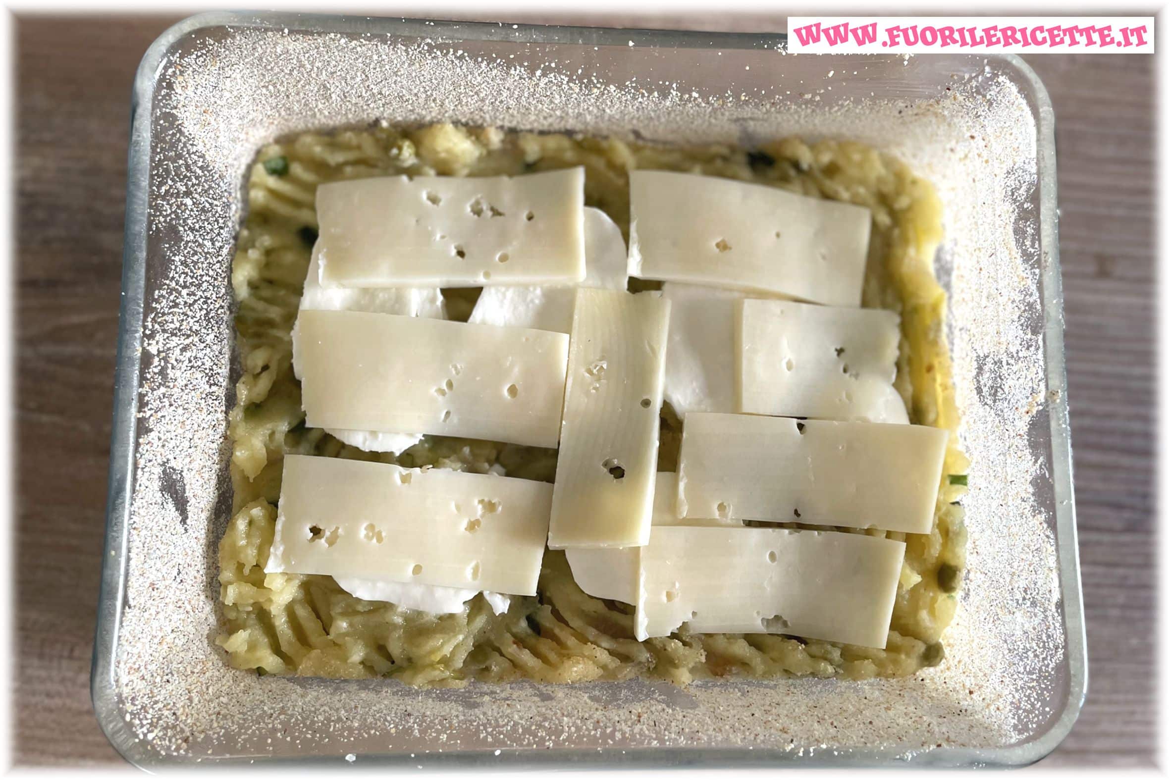 Versiamo metà dell'impasto nella pirofila, aggiungiamo la mozzarella a fette e la provola