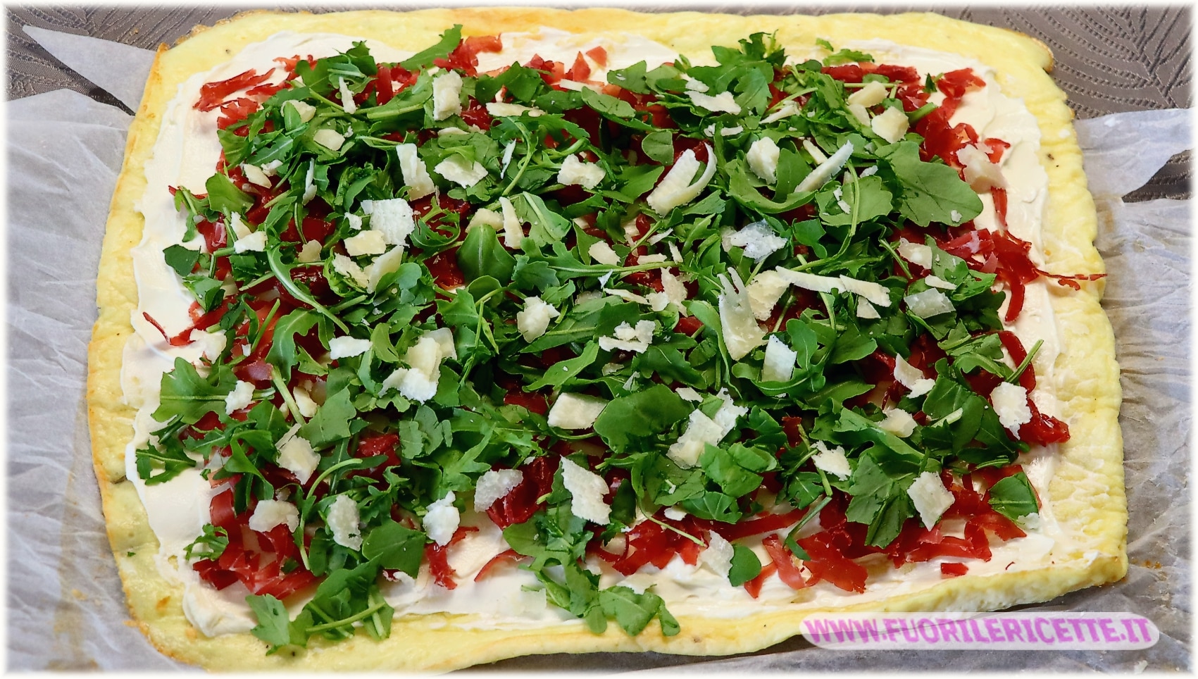 ricoprire con la rucola e in fine sbriciolare sopra le scaglie di parmigiano.
